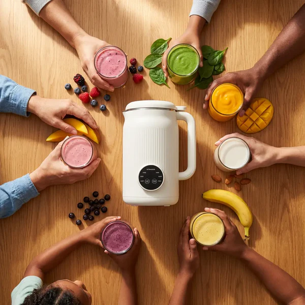 Smoothie aux fruits rouges versé dans un verre à côté du blender Nutrify.